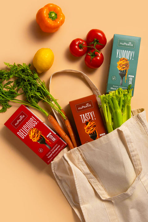 nuPasta boxes with vegetables, in a grocery bag, on a beige background