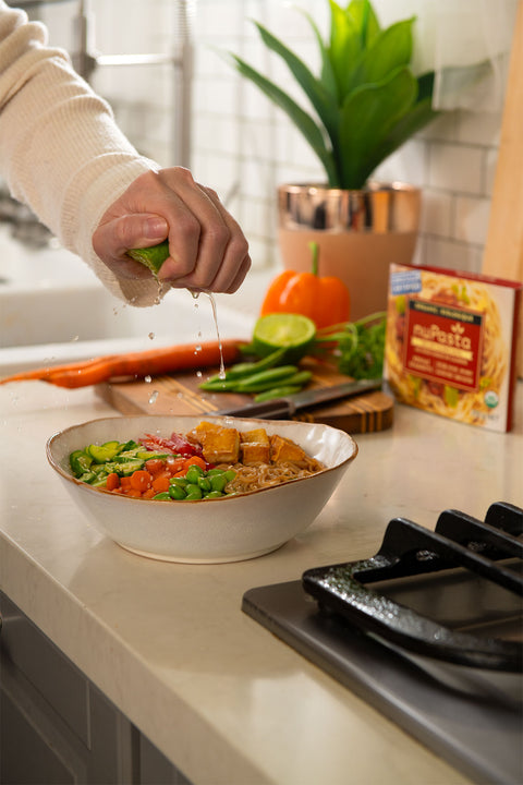 Person preparing a salad with a bowl of ingredients on a kitchen counter.