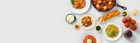 Assorted dishes including pasta, bread, and vegetables on a white background